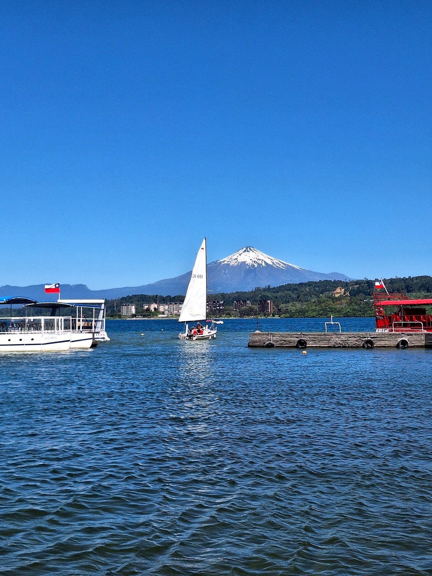 Velero con la vela arriba navegando frente al volcán Villarrica